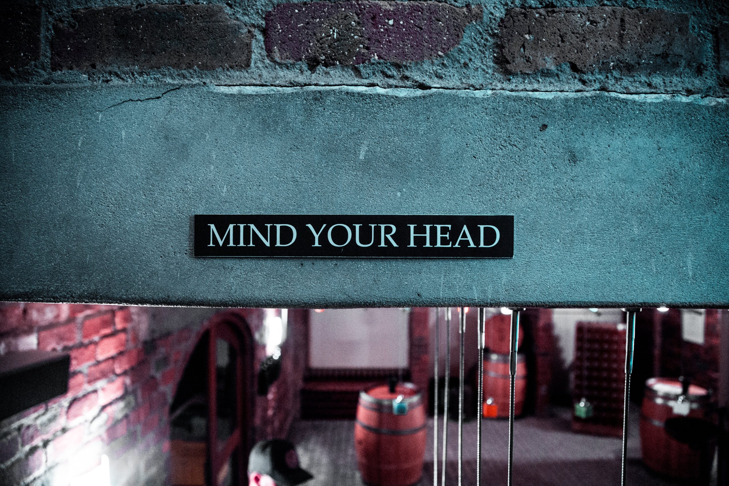 A sign on a brick wall that says, "Mind your head."