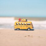 A small yellow toy van on a sandy beach