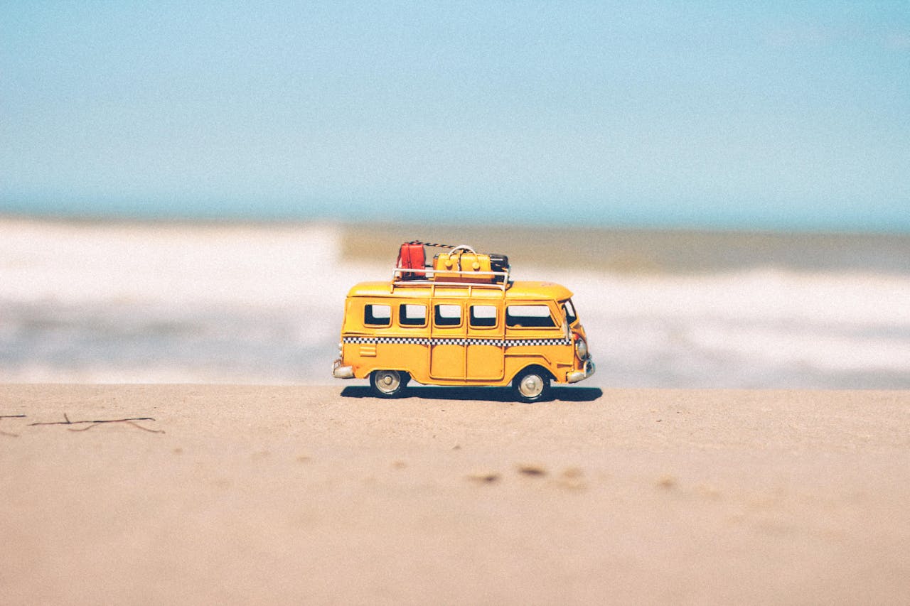 A small yellow toy van on a sandy beach