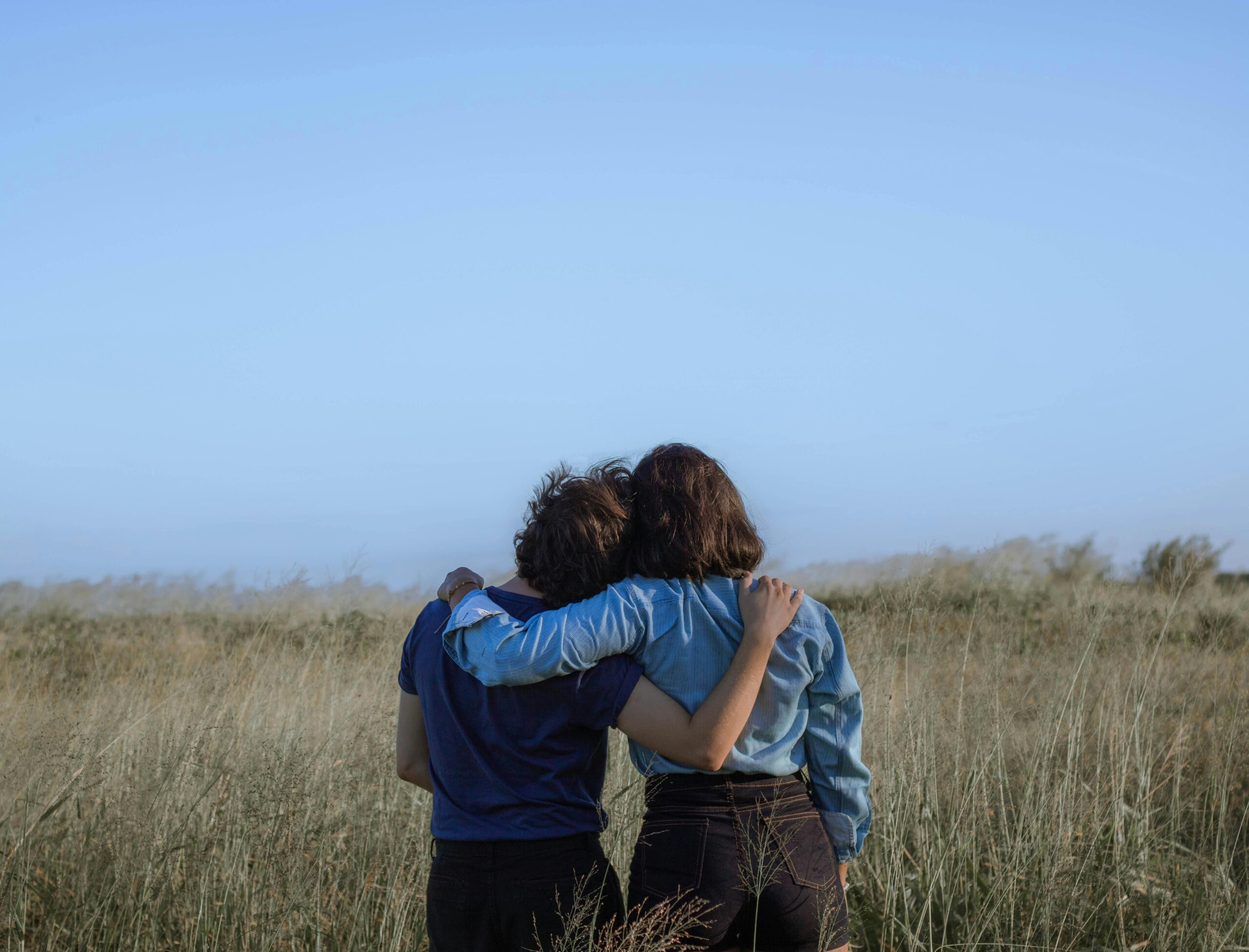 photo taken behind two friends who are embracing