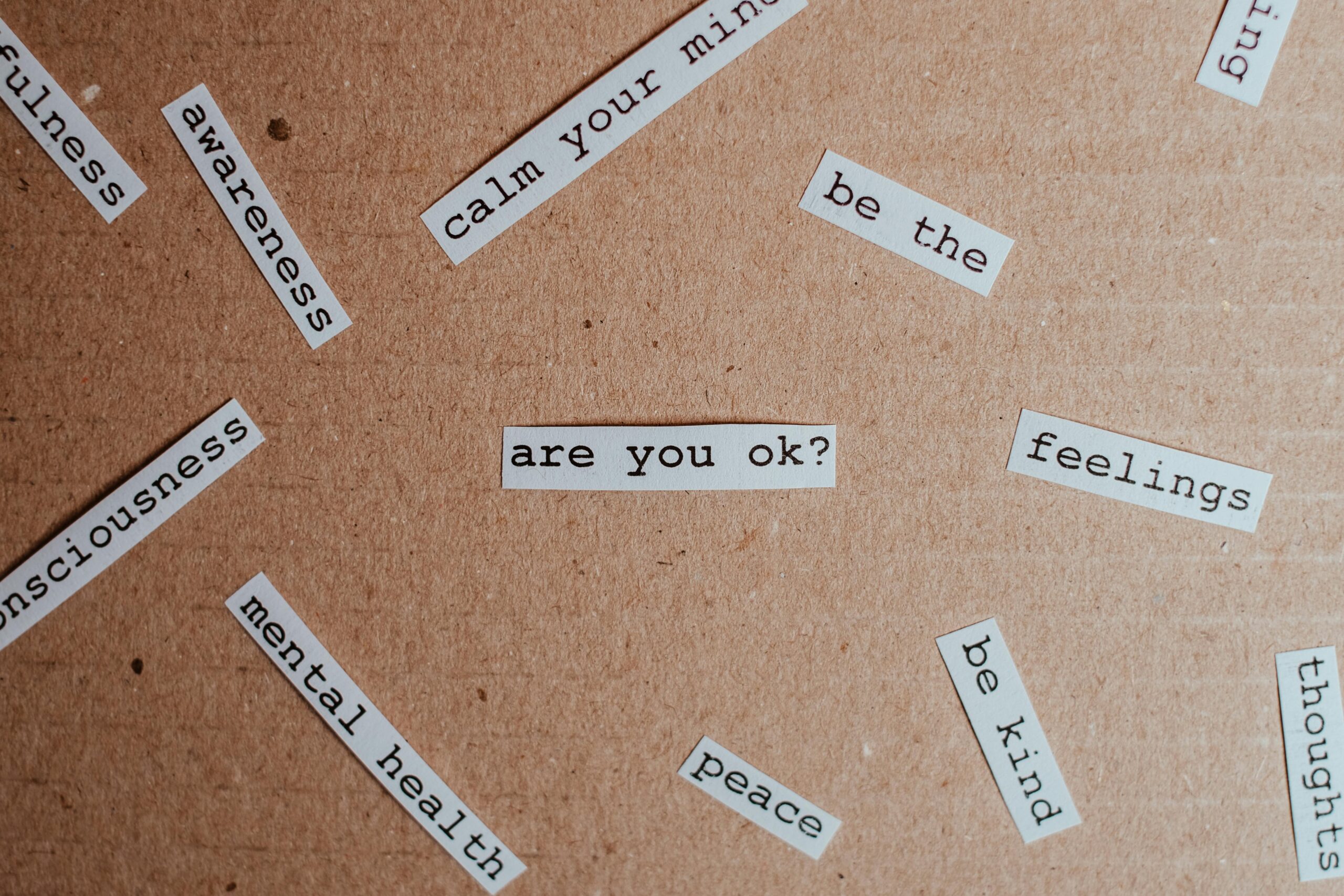 words related to mental health cut out and placed on a corkboard background