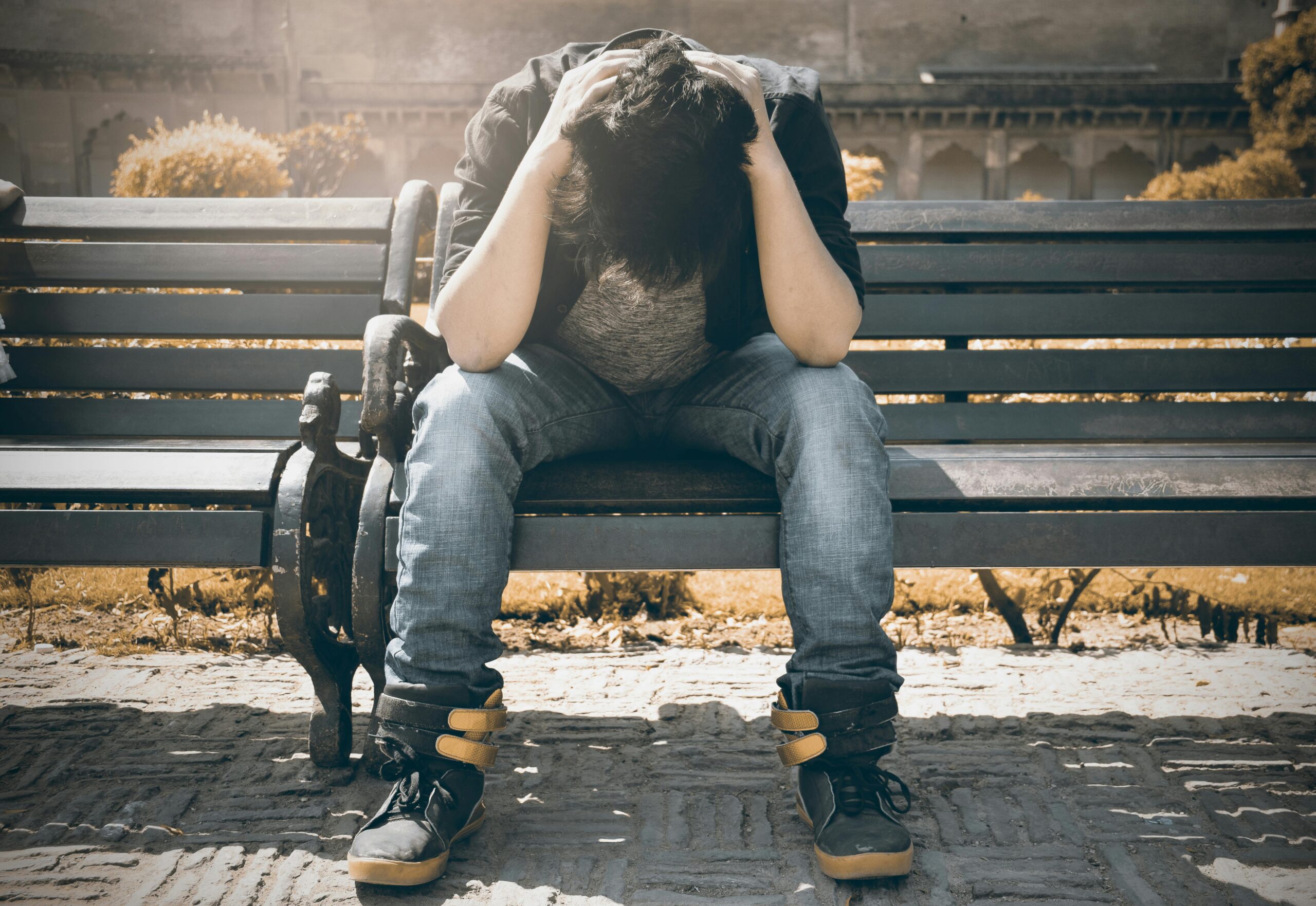 young man bent over on a bench